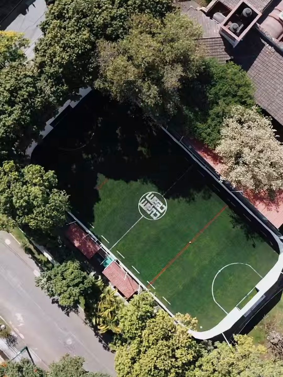 Cancha de fútbol del CEAM en Cuernavaca vista desde arriba, rodeada de árboles, con un logo al centro