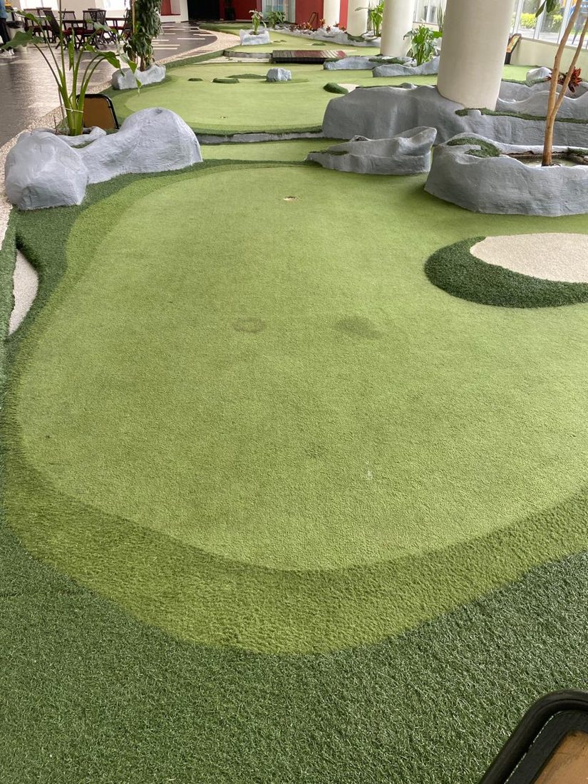 Minigolf de pasto sintético en dos tonos de verde con rocas decorativas