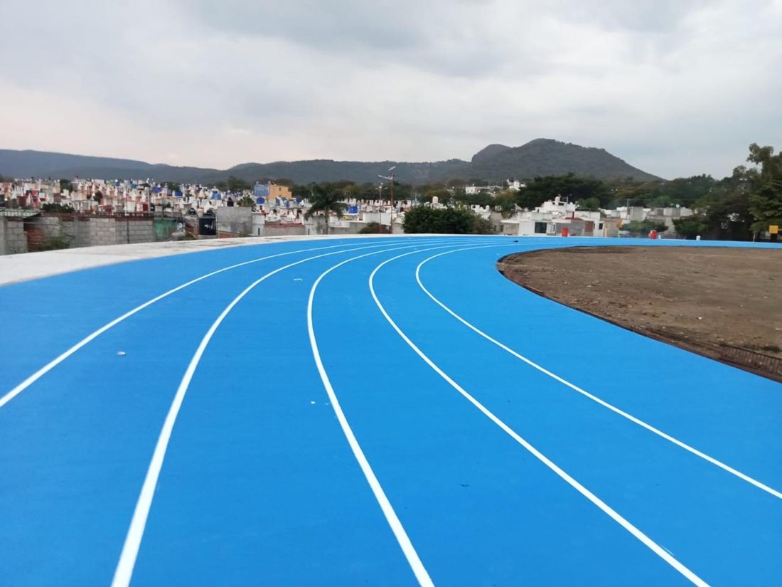 Curva de una pista de atletismo azul con carriles blancos y el centro todavía de tierra
